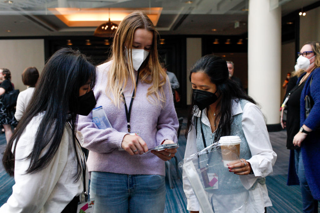 Three people wearing N95 masks viewing someone in the person in the center's hands.